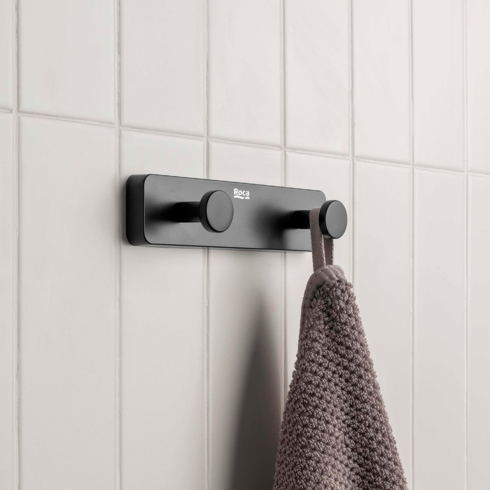 Lifestyle image of the Roca Sonata Matt Black Double Robe Hook mounted on a bathroom wall and hanging a towel